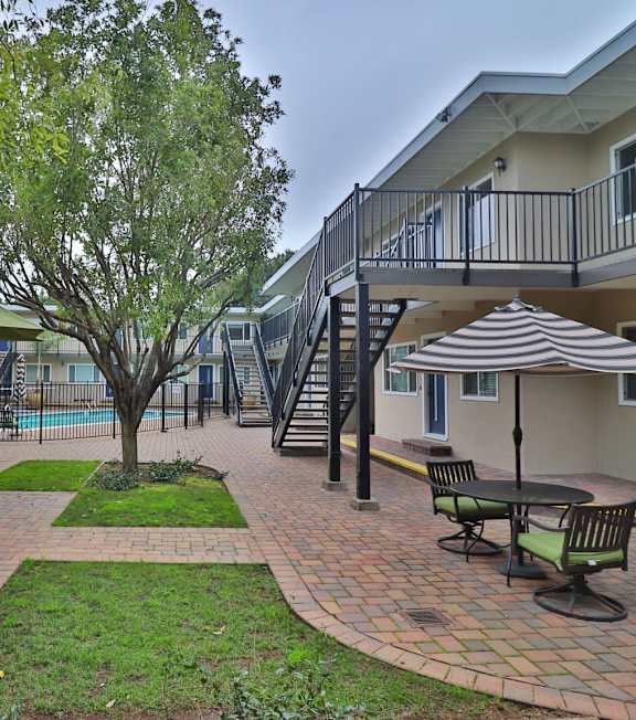 a patio with chairs and a table in a courtyard