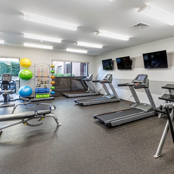 a gym with treadmills and other exercise equipment and televisions at The Collings at the Lumberyard, Collingswood, 08108