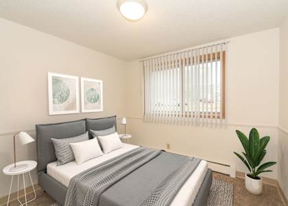 A bedroom with a bed, a plant, and two pictures on the wall.