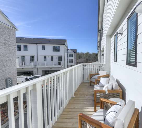 A white building with a balcony has chairs and a table on it.