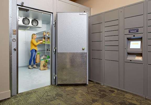 A woman is standing in a room with a refrigerator and an ATM.