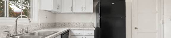 Van Nuys Apartments for Rent - Colonial Manor Modern Kitchen with Black Appliances, White Cabinetry, and Large Window