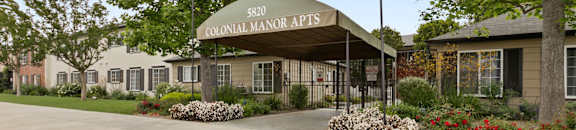 Apartments for rent in Van Nuys - Exterior View of Colonial Manor Apartments in Van Nuys with Gated Entrance and Lush Landscaping