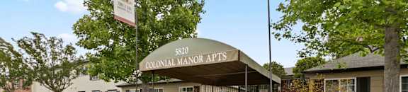 Apartments for rent in Van Nuys - Exterior View of Colonial Manor Apartments in Van Nuys with Gated Entrance and Lush Landscaping