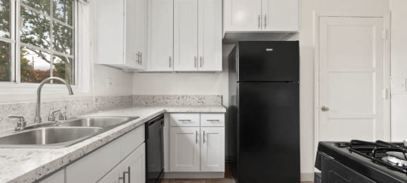 Van Nuys Apartments for Rent - Colonial Manor Modern Kitchen with Black Appliances, White Cabinetry, and Large Window