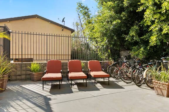 Apartments in Mar Vista CA - Vista - Outdoor Courtyard with Orange Cushioned Lounge Chairs, with Bike Rack, Trees, and Potted Plants