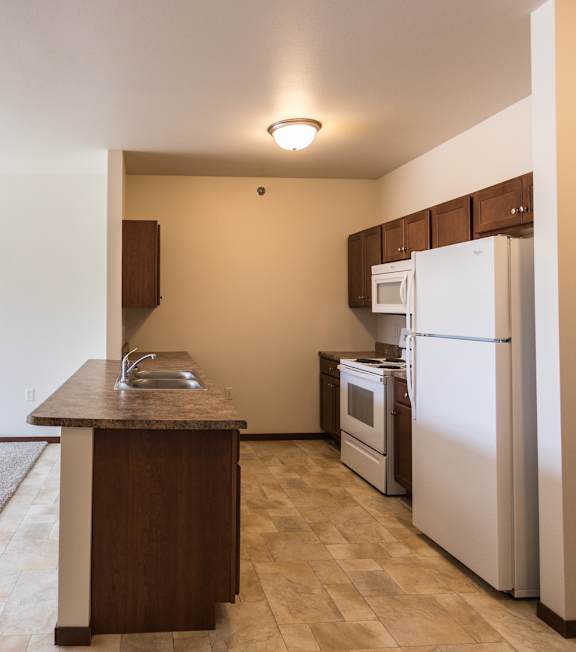 A kitchen with a white refrigerator and a wooden island.