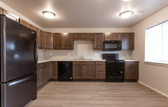 A kitchen with brown cabinets and a black refrigerator.