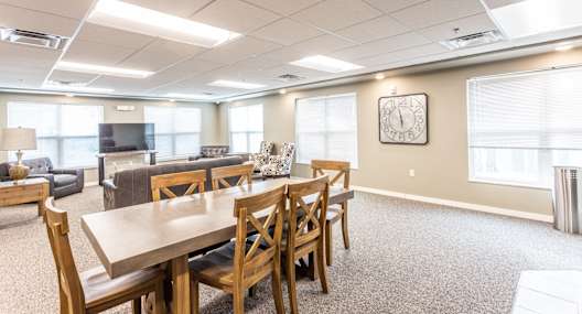 a community room with tables and chairs and a tv