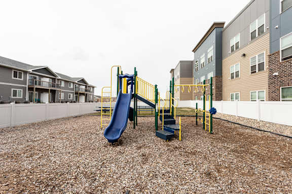 A playground with a blue slide and yellow railing.