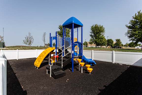 A playground with a blue structure and yellow slide.