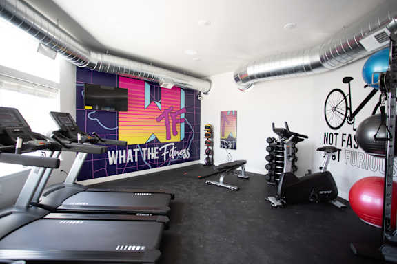 A gym with treadmills, weights, and exercise equipment.