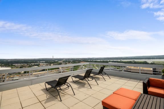 A balcony with chairs and a table overlooking a cityscape. at Lenox Club Apartments, Arlington, VA, 22202