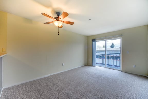 A room with a ceiling fan and carpeted floor.