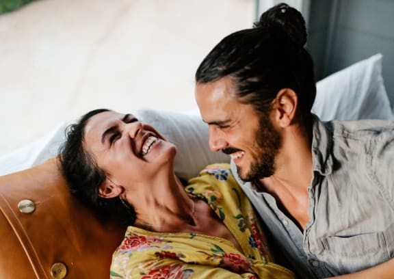 a man and a woman laying on a couch laughing