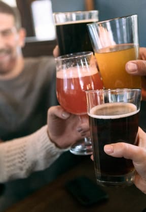 three people holding up glasses of beer at a bar