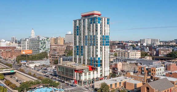 A modern building with a blue and red design stands out in a cityscape.