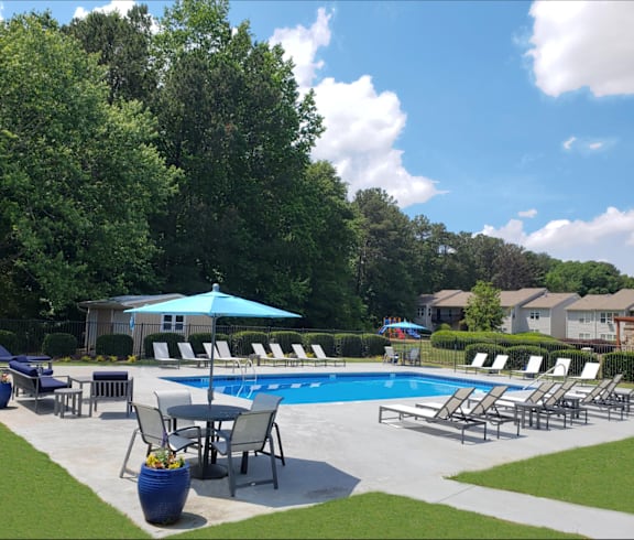 a swimming pool with chairs and umbrellas in a yard