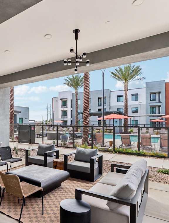 A modern dining area with a black sofa, round tables, and hanging lights at Ironwood Ranch Apartments,Maricopa,85138