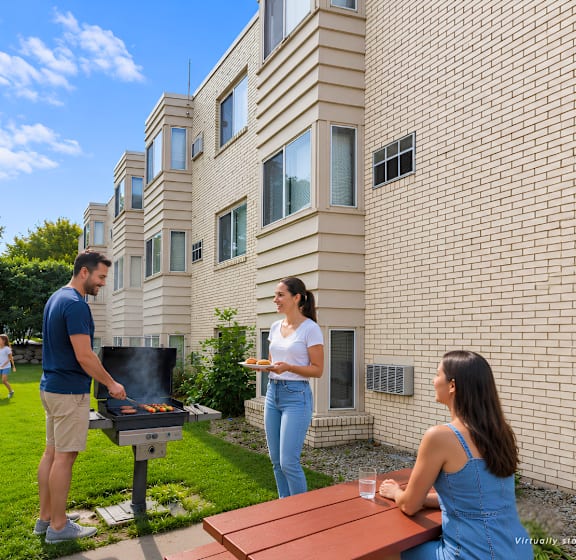 A man grilling in a backyard with a woman standing nearby and children playing in the background.