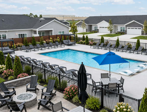A pool surrounded by black chairs and umbrellas.