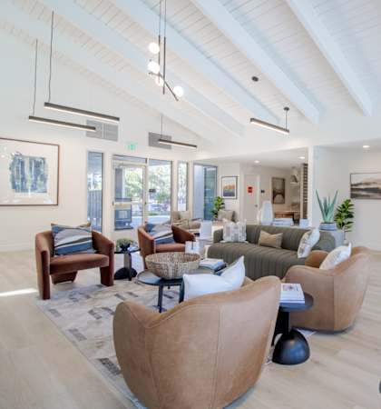A billiard table is in the middle of a spacious room with a couch and chairs.
