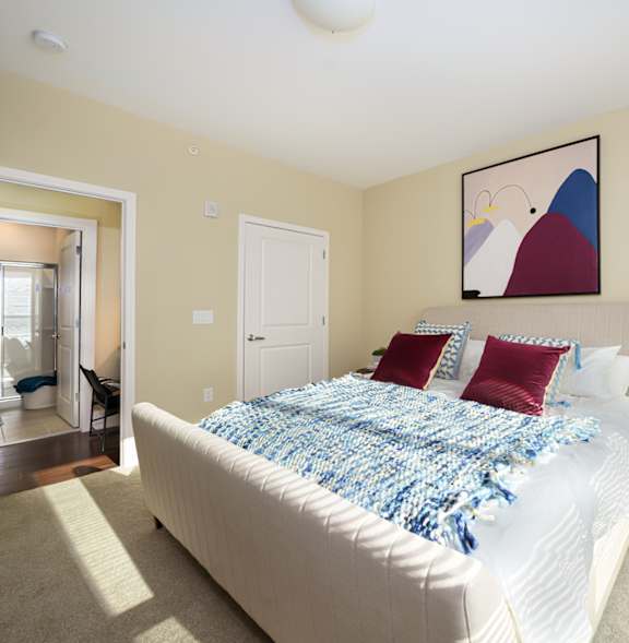 A bedroom with a bed, pillows, and a nightstand.