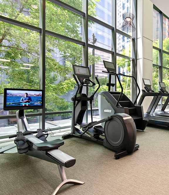 A gym with treadmills, exercise bikes, and a television.