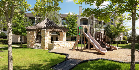 a playground with a slide in front of a house with a gazebo