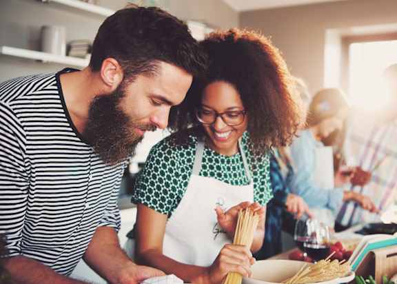 A man and a woman are cooking together in the kitchen.