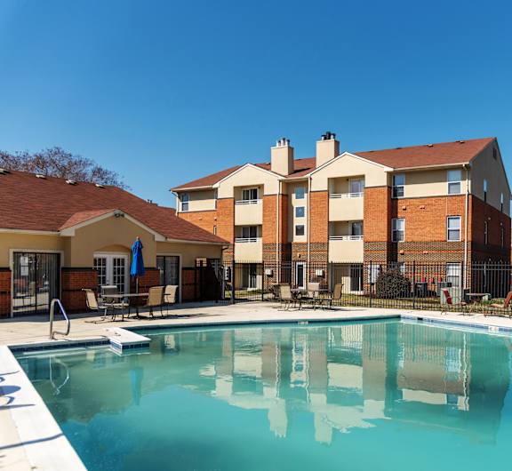 A swimming pool in front of a multi-story apartment building.