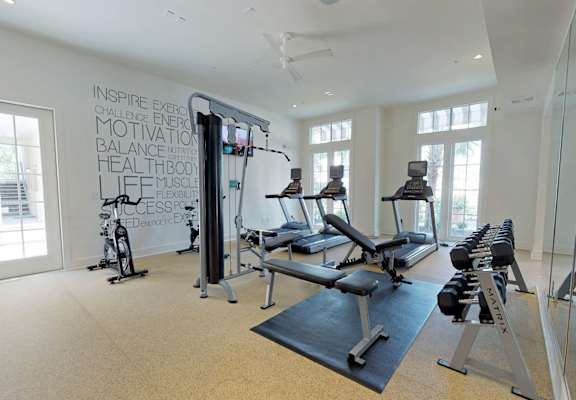 A gym with a variety of equipment including treadmills, stationary bikes, and weight machines.