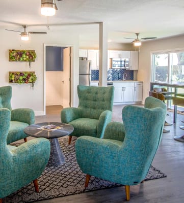 a living room with green chairs and a kitchen in the background at Woodland Crossing , Woodland, 95695