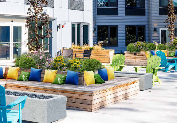 a patio with blue chairs and wooden benches and plants