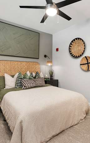 A bedroom with a bed, nightstand, and wall decor.