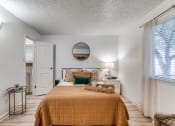 Thumbnail 4 of 43 - Renovated bedroom in Fusion Fort Worth, previously Desert Sands apartments. Large bed with camel duvet and green velvet pillow next to midcentury modern bar cart with succulent.