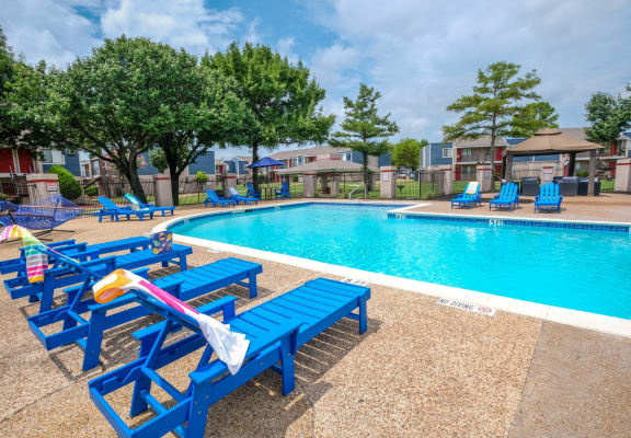 Fusion Fort Worth swimming pool with blue chaise lounge chairs and trees in the background