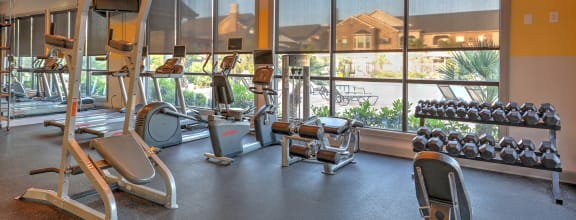 a gym with cardio equipment and windows with a view of a building