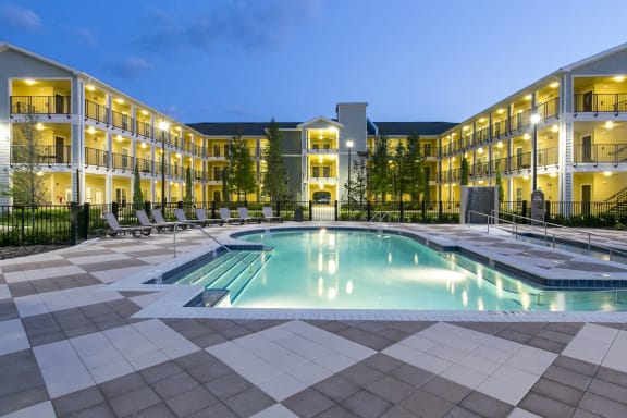 a swimming pool in front of a hotel at night