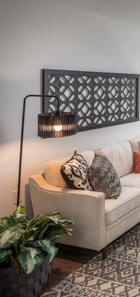 A living room with a white couch, a glass coffee table, and a large window.