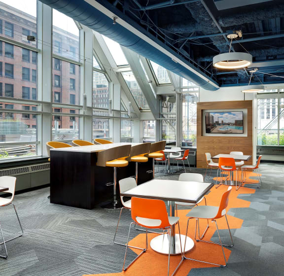 a cafeteria area with tables and chairs and large windows at Galtier Towers Apartments, St. Paul