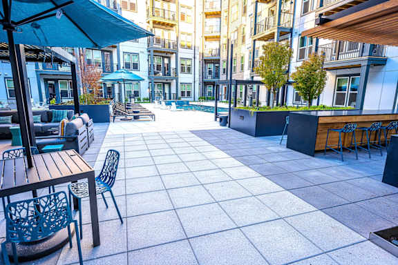 A patio with tables and chairs is surrounded by buildings.
