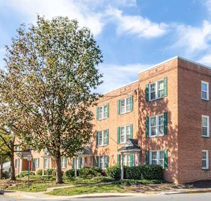 A red brick building with green shutters on the windows at The Fields of Rockville, Maryland