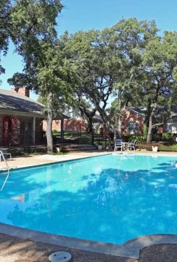 A blue umbrella is over a chair by a pool.