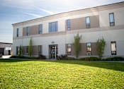 Thumbnail 1 of 4 - A modern building with a green lawn in front.