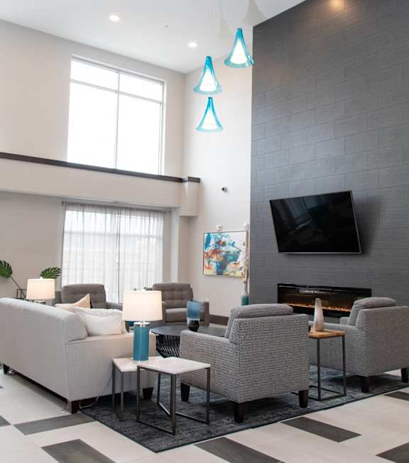 A living room with a grey couch, a fireplace, and a television at Avonlea in Lakeville, MN