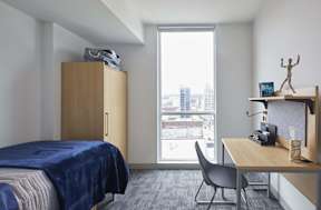 A bedroom with a bed, desk, and chair.