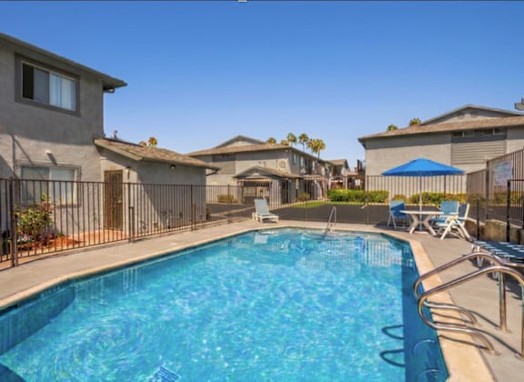 A swimming pool surrounded by a metal fence and chairs.