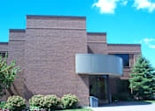 Thumbnail 1 of 3 - A building with a brick facade and a large glass entrance.