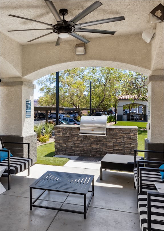 A patio with a table and chairs under a fan.
